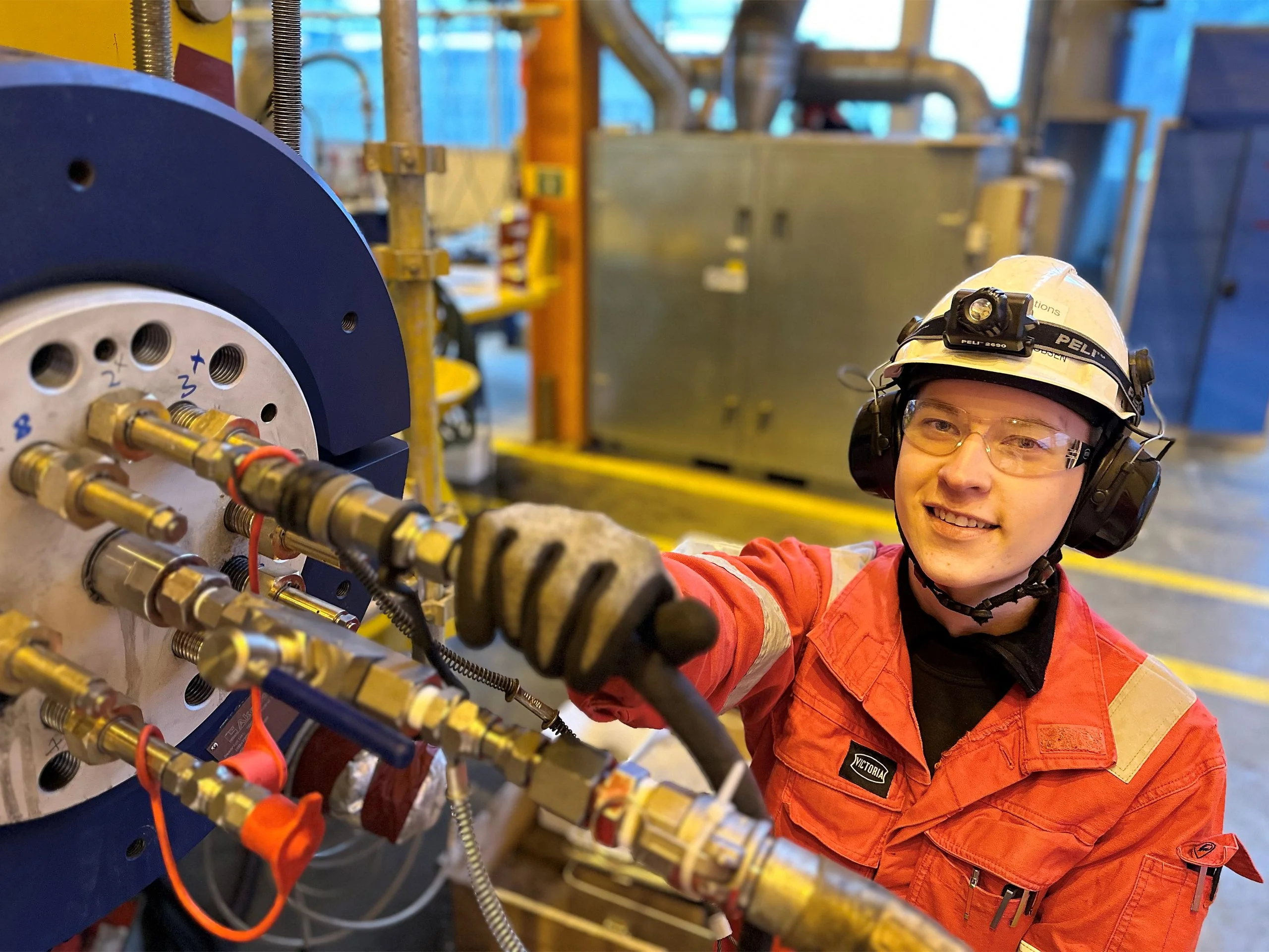 Lucas Jørgensen holder høyre hånd på rørinntaket på en koblingsdel til de store rørene de produserer.