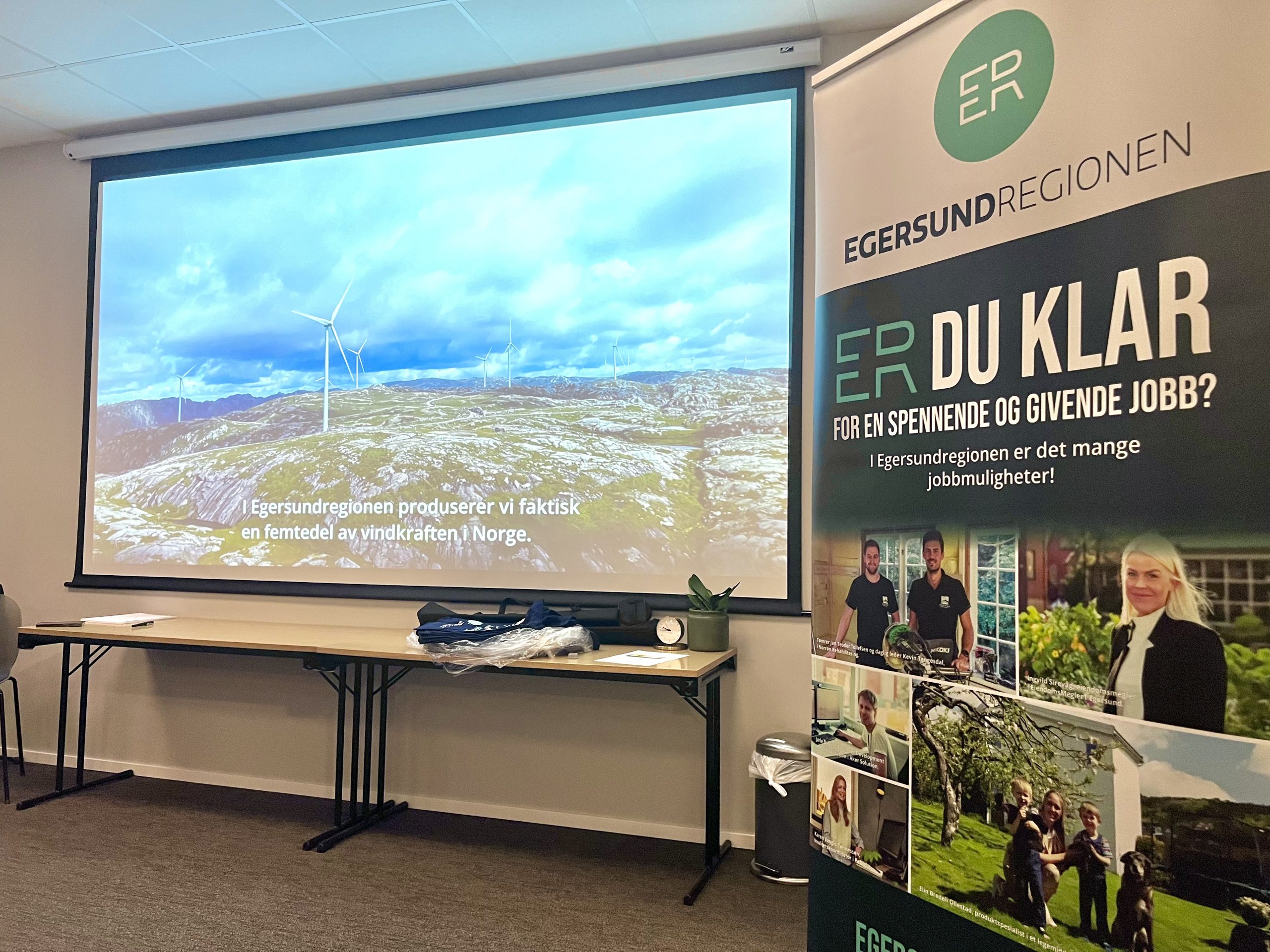 Helene Holm avbildet i t-skjorte med påskriften "jobbene er her", Egersundregionen-logo og kommunene Eigersund, SOkndal, Bjerkreim og SOkndal. Hun holder to svarte flasker i hendene med logo til Sokndal kommune.